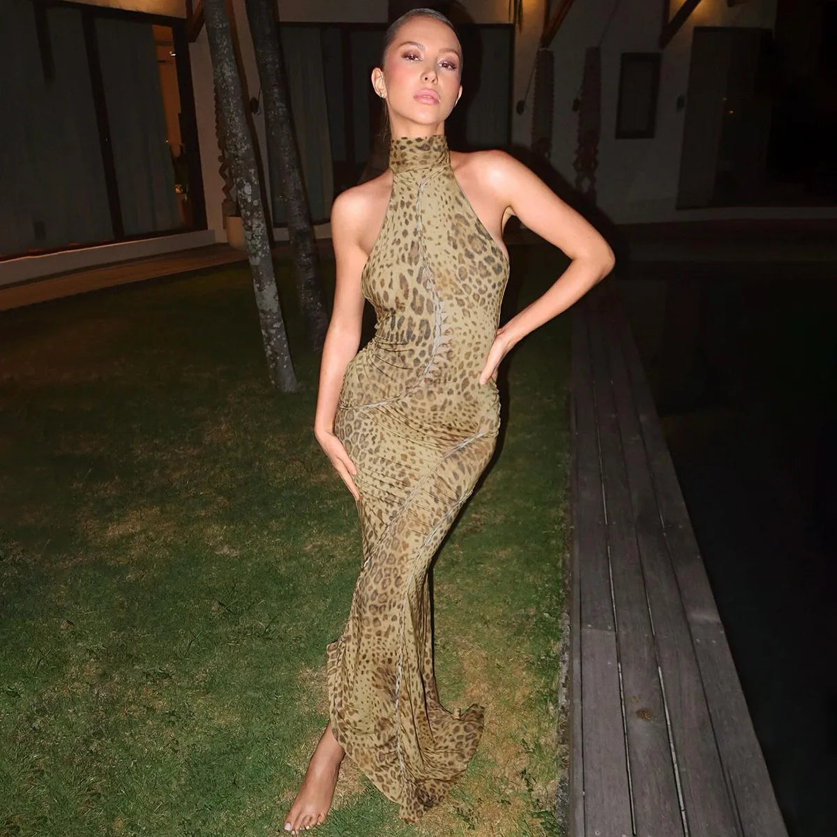 Woman in a leopard print dress standing outdoors at night.