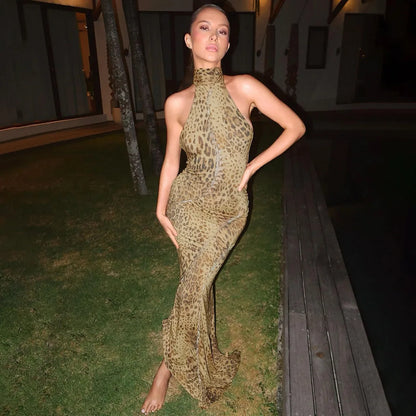 Woman in a leopard print dress standing outdoors at night.